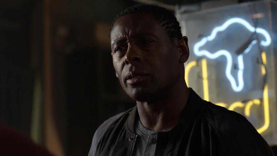 J'onn listens to Dean Petrocelli's anti-alien diatribe.