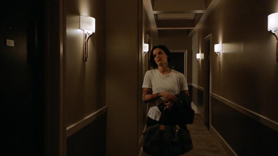 Jane walks down the hallway up to the door of Clem's hotel room.