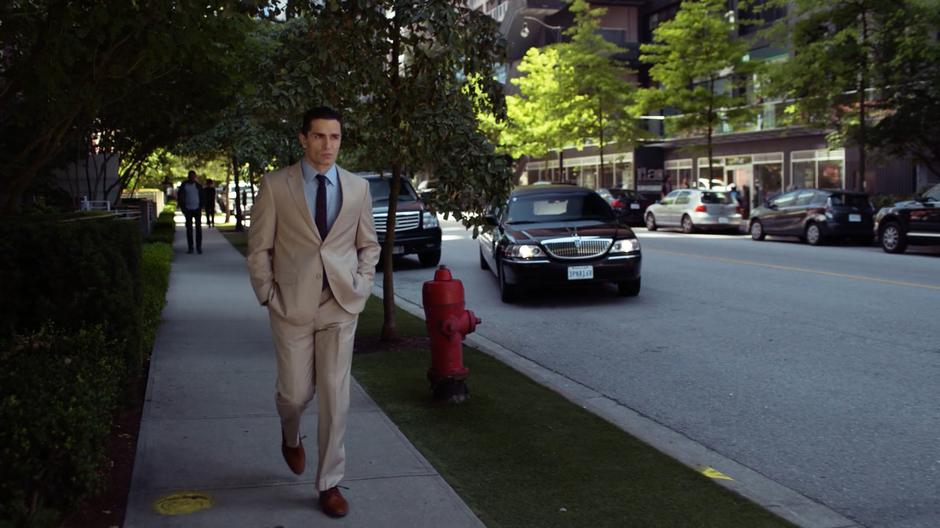 Ben Lockwood walks down the street away from the plaza as a limo pulls up beside him.