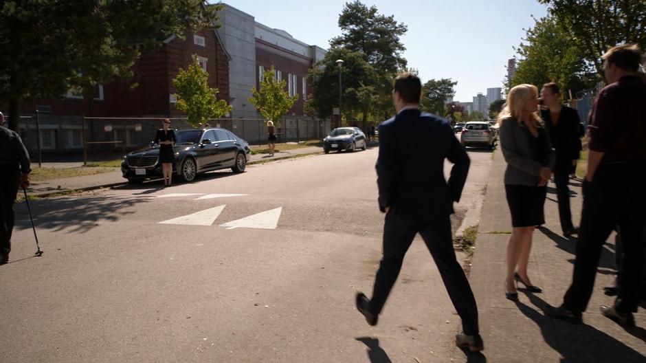 Ben Lockwood cross the street to where Lena is waiting by her car.