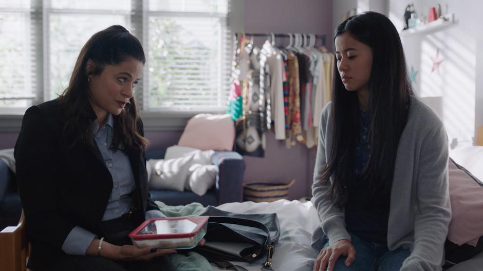 Mel offers Angela Wu a cookie while they sit on Angela's bed.