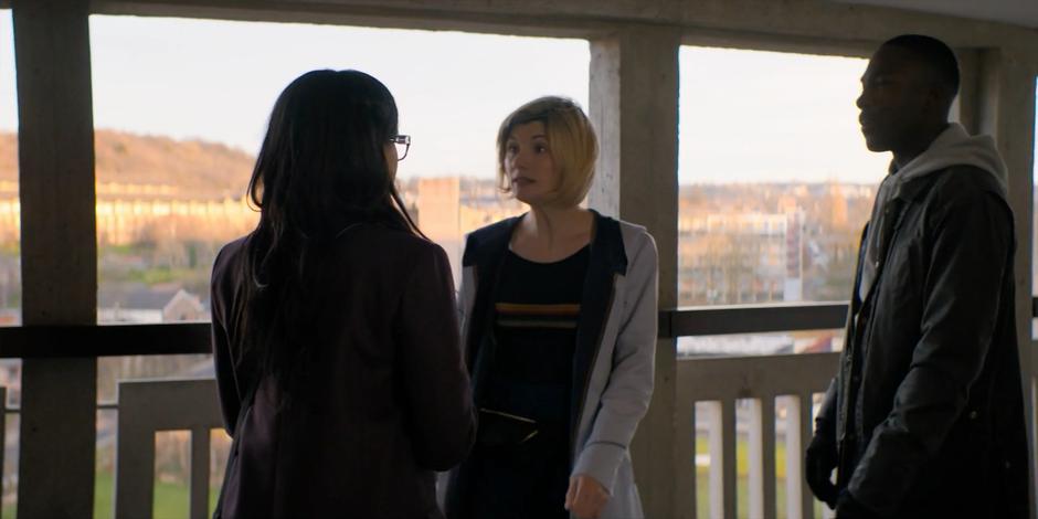 The Doctor and Ryan talk to Jade outside Anna's apartment.