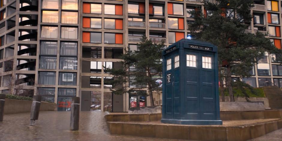 The TARDIS materializes on the walkway in front of the estate.