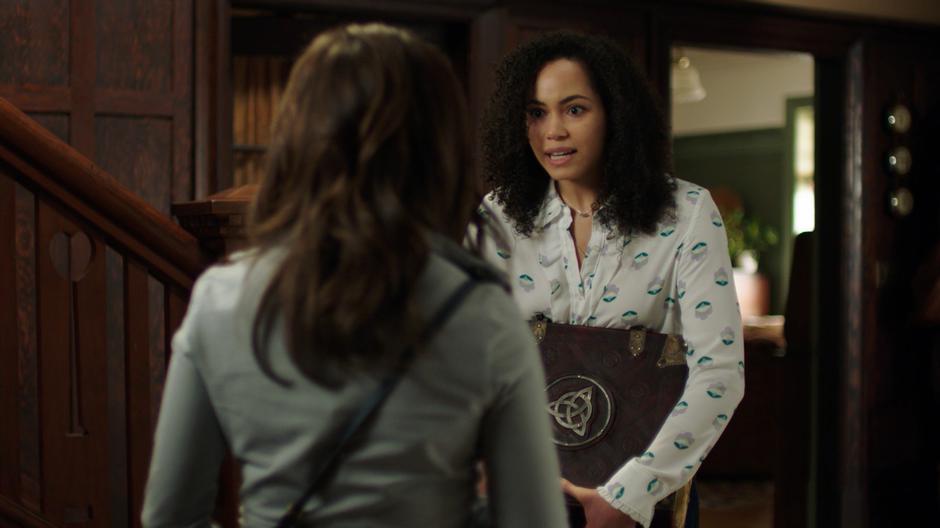 Macy excitedly talks to Maggie in the entryway while holding the Book of Shadows.