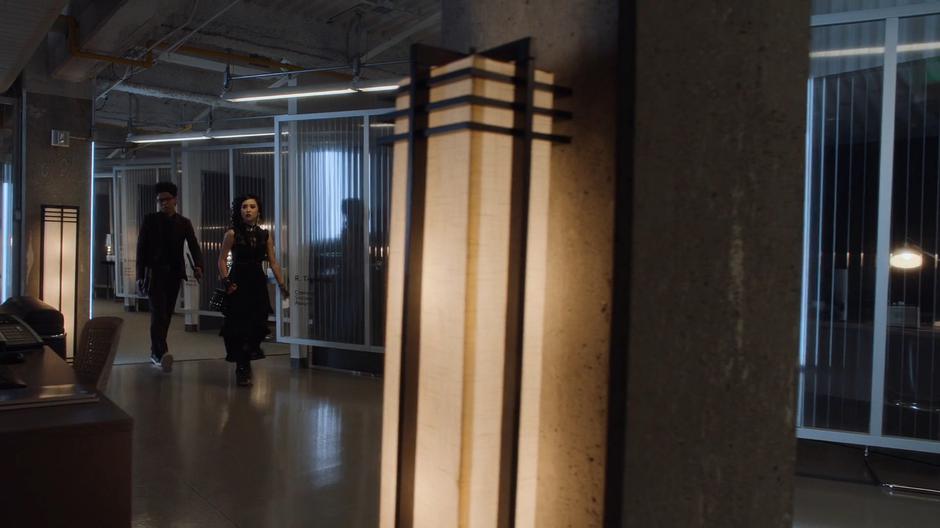 Alex and Nico walk through the office level towards Tina's office.