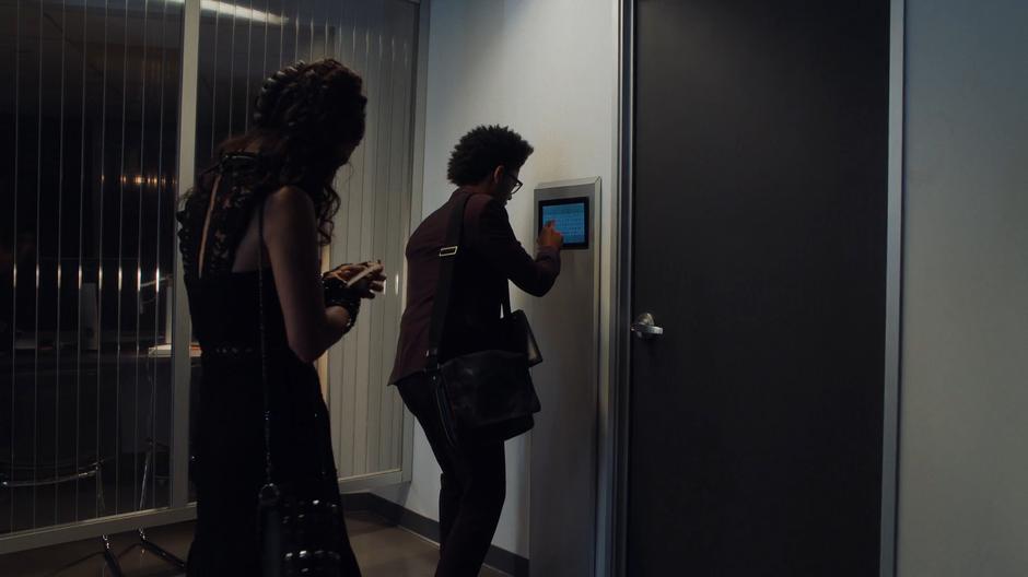Nico checks her phone while Alex tries a password on the door to the office.