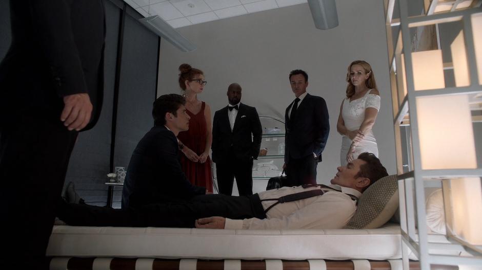 Chase sits on the bed with his father while Stacey, Geoffrey, Jonah, and Leslie stand over him.
