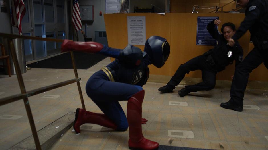 Kara lands on the lower level of the lobby and turns to fight one of the alien duplicates.