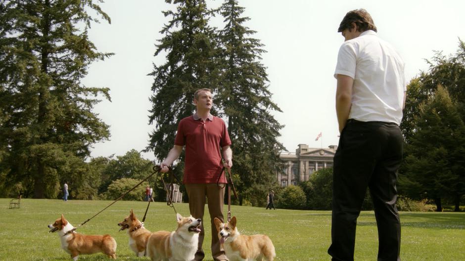 Ray asks the dog walker to borrow one of the corgis while he looks terrified at Sara over Ray's shoulder.