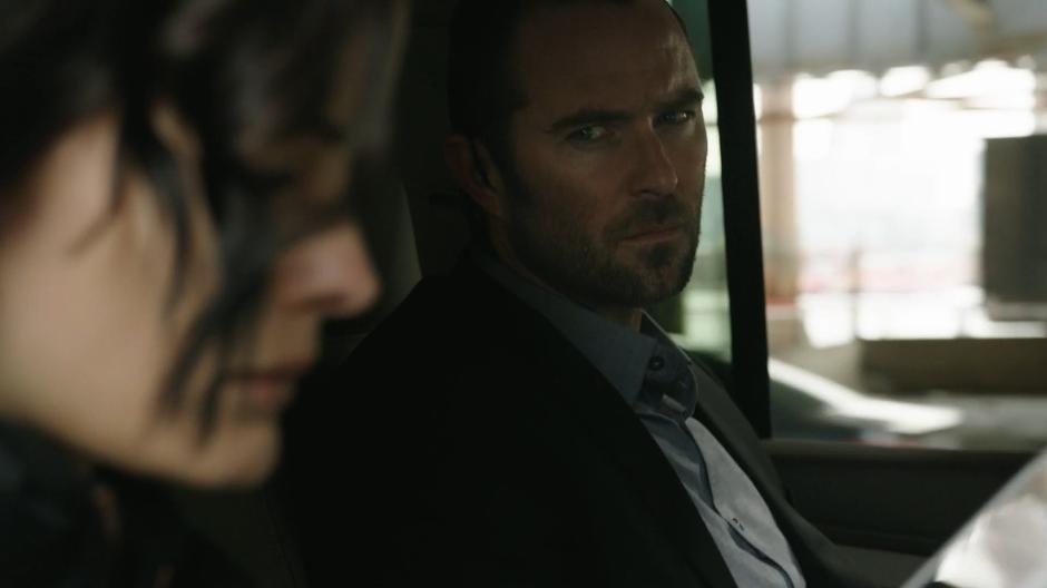 Kurt looks over at Jane as they sit in the back of the SUV.
