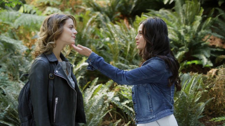 Nina puts her hand under Izzy's chin while they talk in the courtyard.