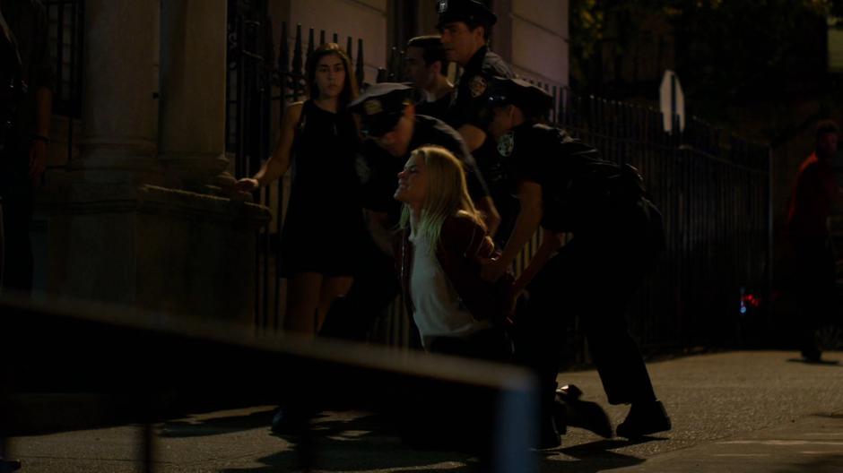 Trish is wrestled to the ground by several police officers.