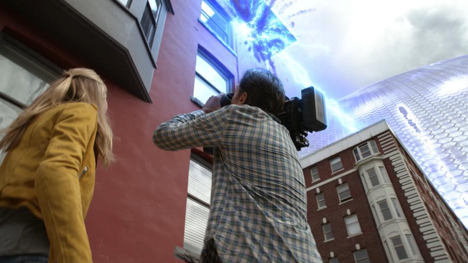 A laser blast from Jensen shoot out of the dome and into a building above a news crew.