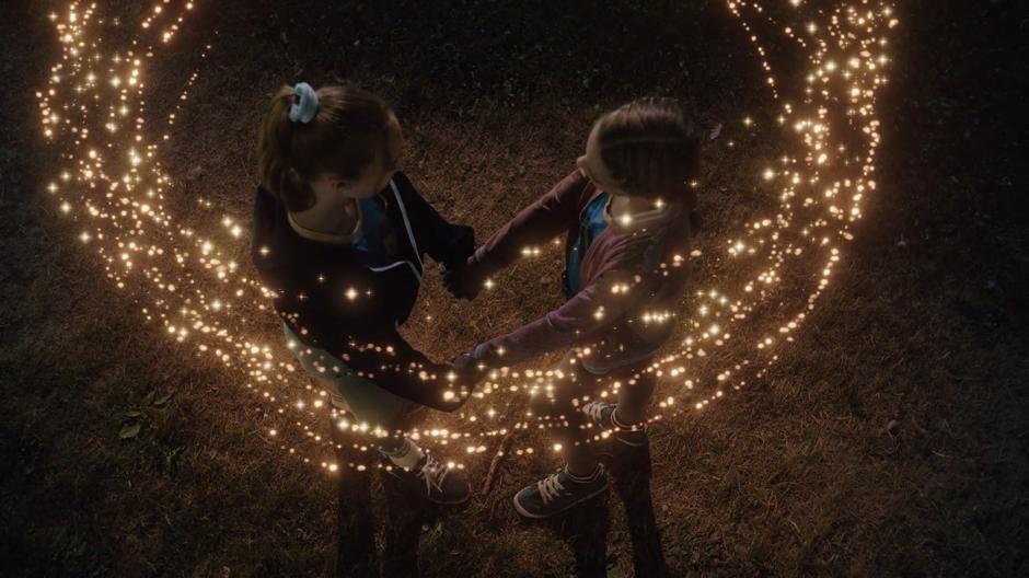 12-year-old Ava and Sara hold hands while the circle of light appears around them.