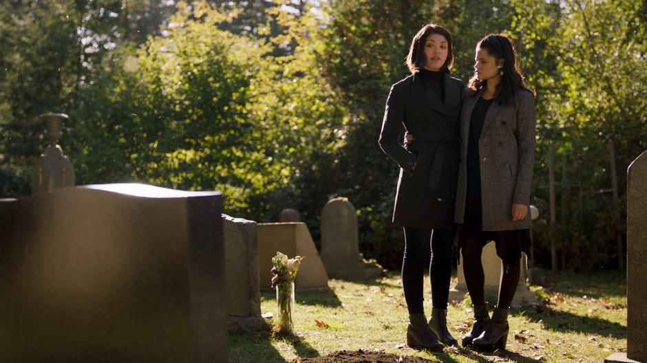 Mel stands with her arm around Niko while they stand in front of Trip's grave.