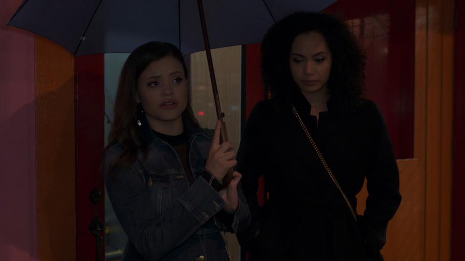 Maggie holds the umbrella as she walks out of the apartment building with Macy.