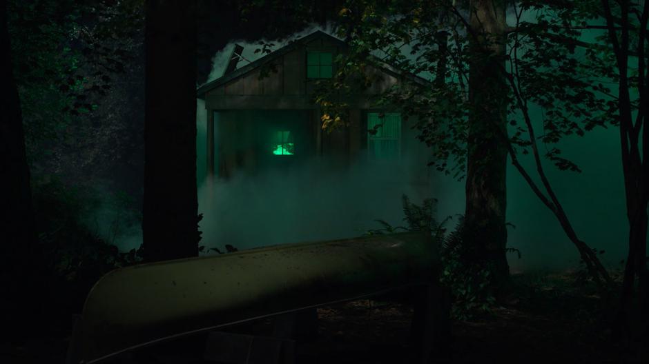 The cabin burns with an eerie green flame.