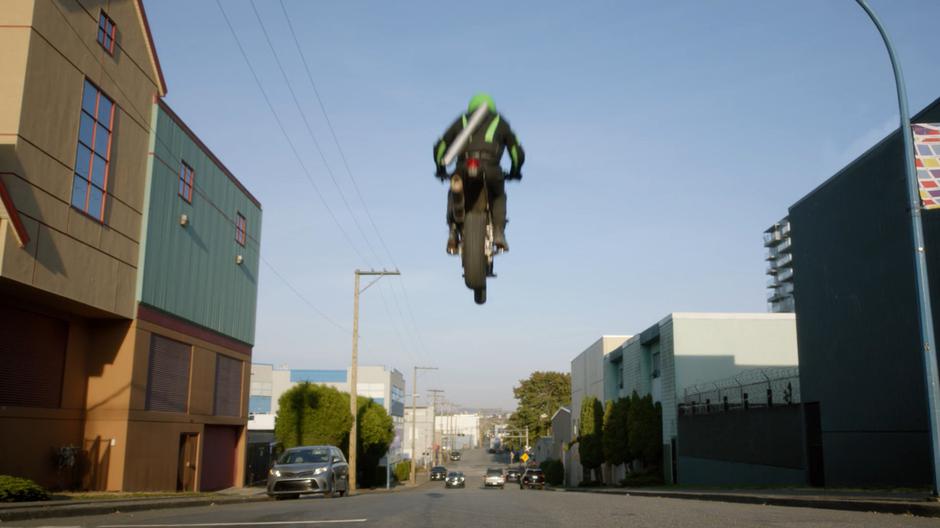 The art thief flies through the air on their motorcycle.