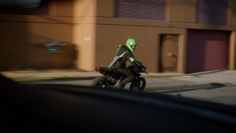 The motorcyclist glances back at the police car following them.