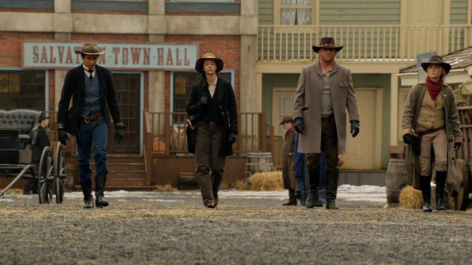 Wally, Zari, Mick, and Sara strut down the street in their cowboy outfits.