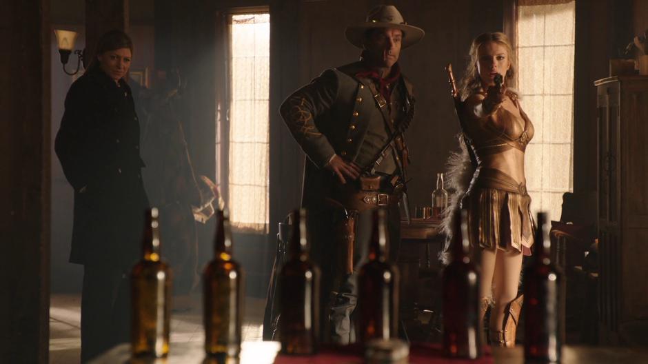 Ava and Jonah Hex watch as Helen practices with a pistol.