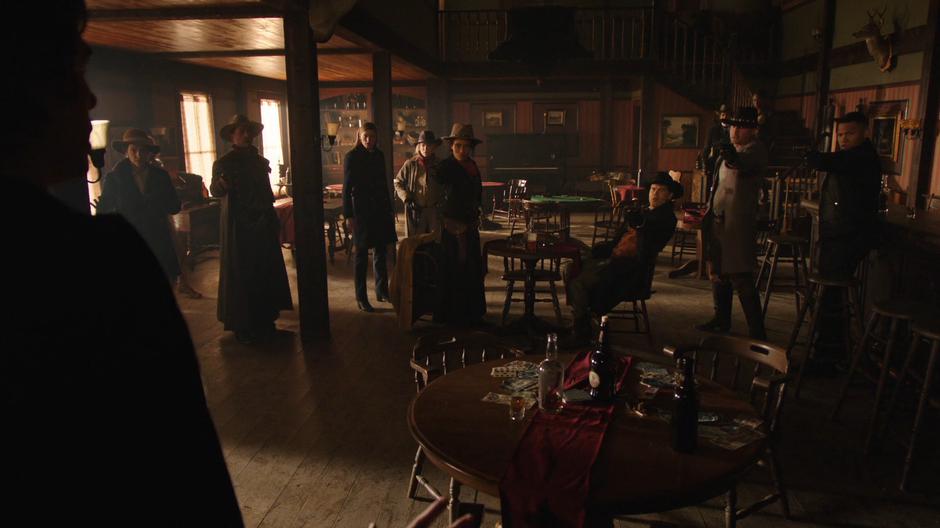 The Legends point their weapons as Nora as she enters the saloon.