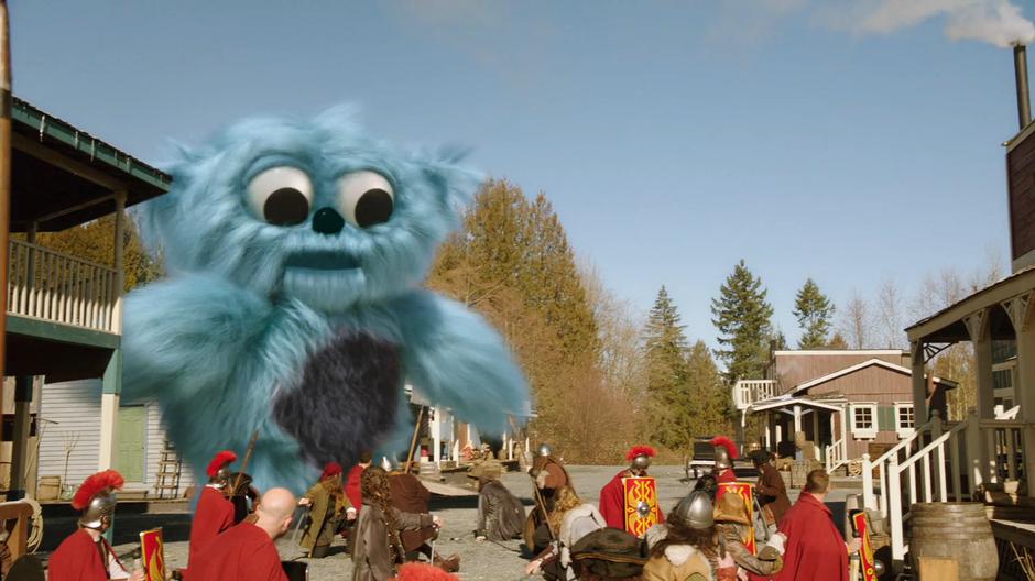 The soldiers in the army back up as a giant Beebo walks down the street.