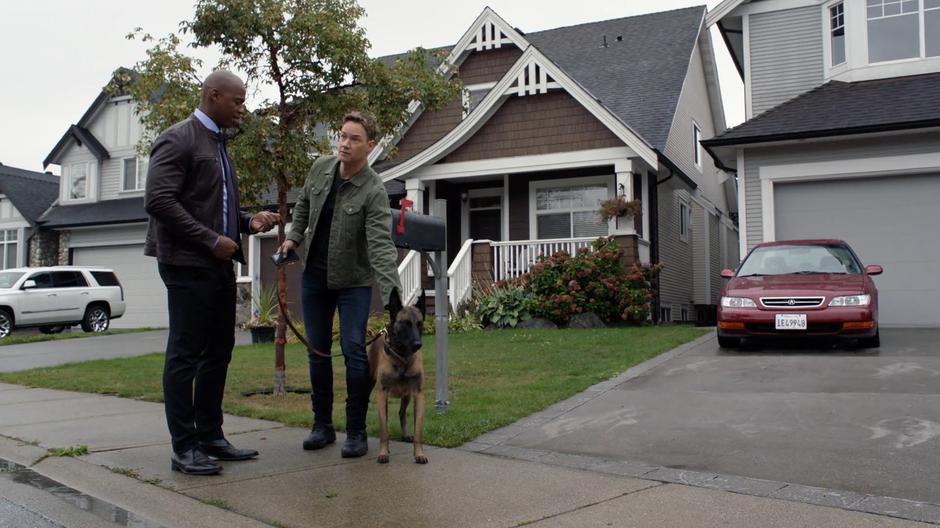 James takes the leash of Tom's dog for him so he can do something.