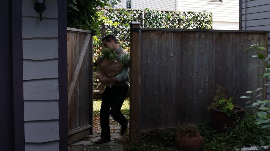 Ben Lockwood enters his back yard while talking on the phone and holding a bag of groceries.