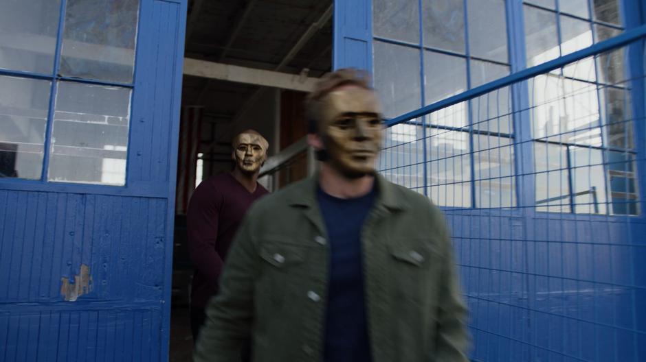 James follows Tom out of the building as they both wear Children of Liberty masks.