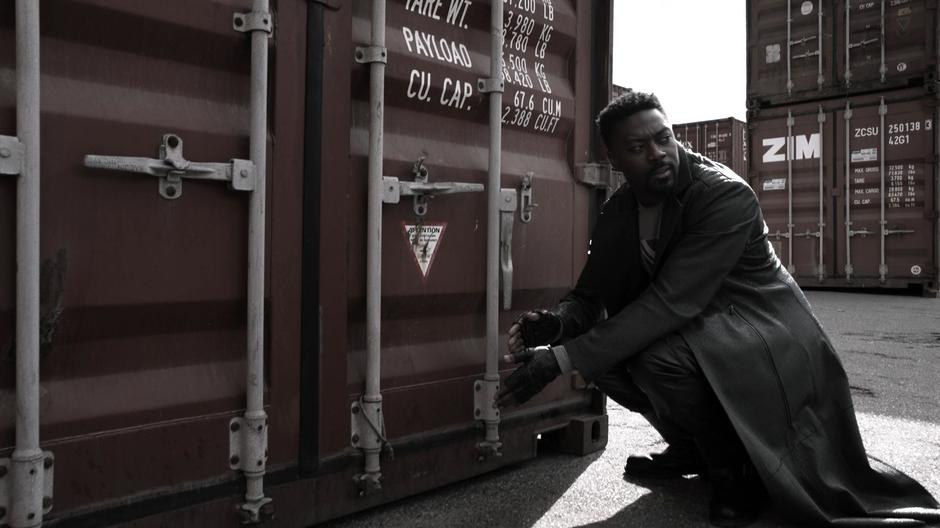 In a flashback, Manchester kneels down next to the container to plant his evidence.