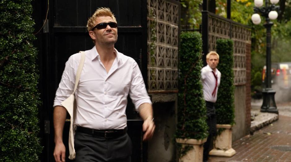 The present day Constantine hides behind a bush while his past self exits his apartment.