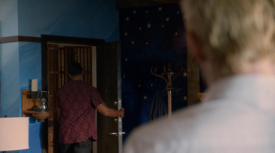 Constantine watches as Des walks out through the door.