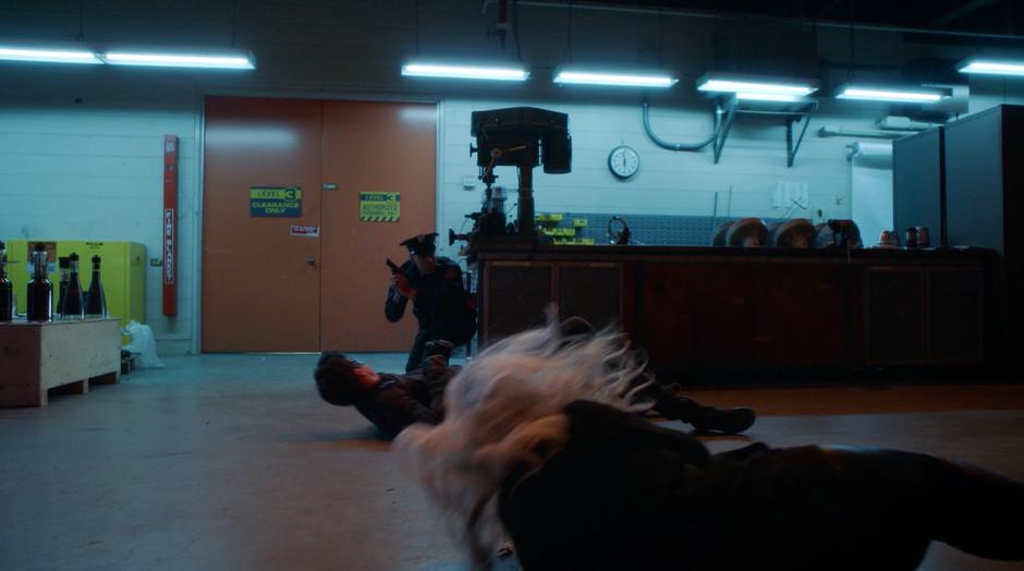 Ralph and Killer Frost are thrown backwards by Amazo as the security guard hides behind a table.