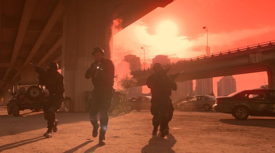 Diggle and three A.R.G.U.S. agents walk through the empty lot under a red sky.