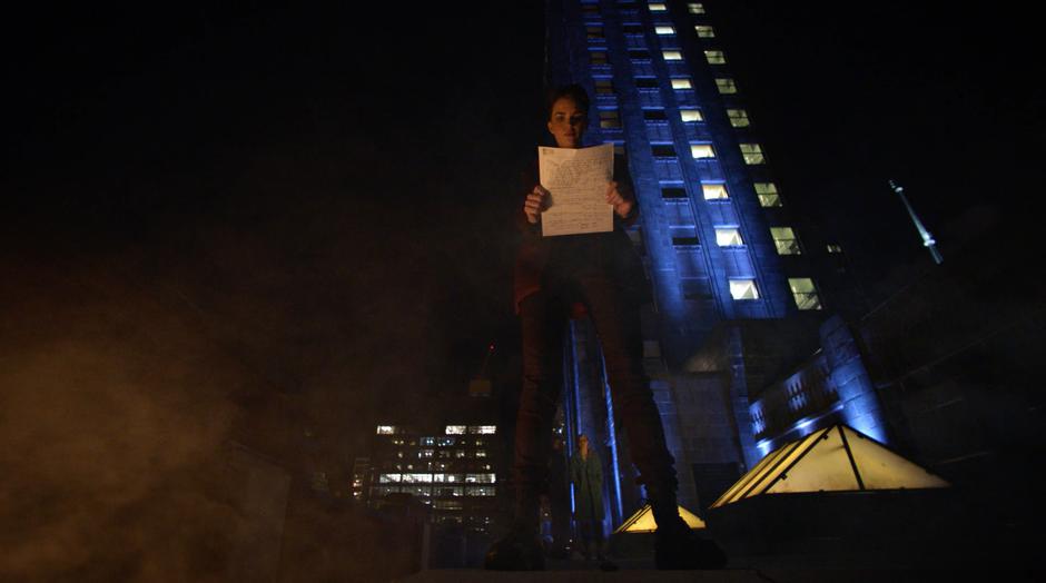 Kate Kane examines Oliver's drawing of the mysterious man while Oliver and Kara wait on the rooftop.