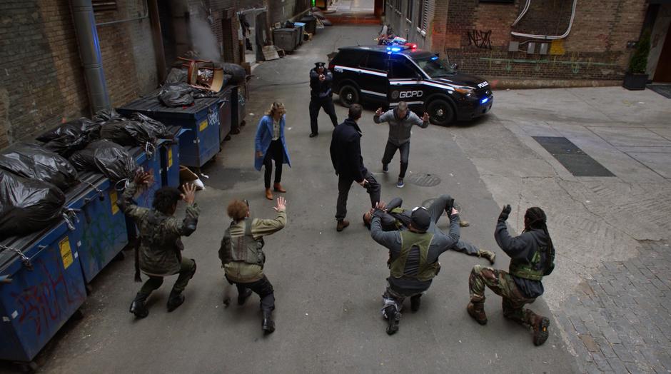 Kara, Oliver, and the muggers surrender while Barry points his gun at one of the muggers as the police approach.