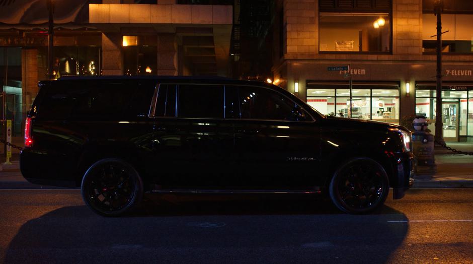 A black SUV sits waiting on the street in front of the station.