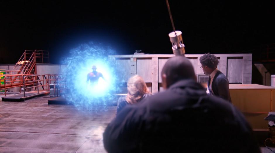 Felicity, Diggle, and Curtis look as the Earth-90 Flash partially emerges from a breach.