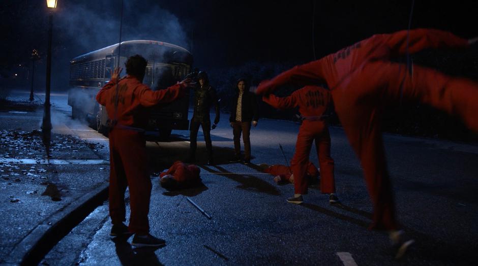 Barry and Cisco stand in front of several inmates as they are lifted up into the air.