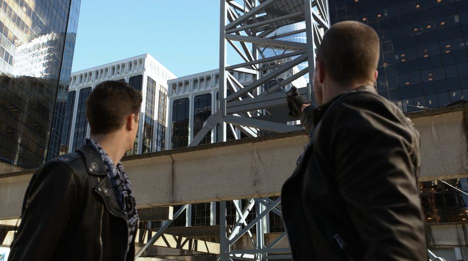 Oliver turns with Barry to shoot a wire holding up the crane.