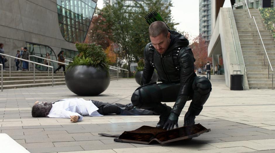 Oliver kneels over the scorched book as a scarred Deegan lies on the ground behind him.