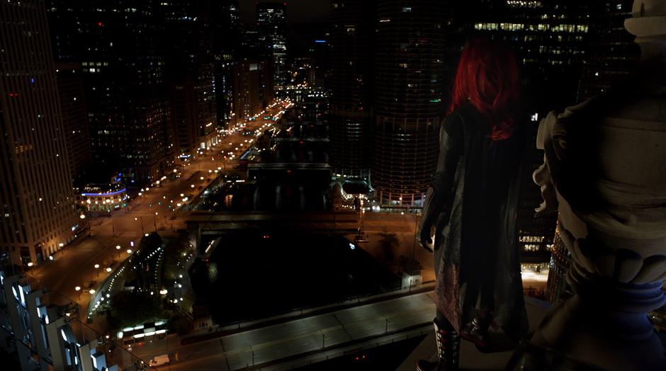 Kate Kane stands on the edge of the rooftop looking over Gotham City.