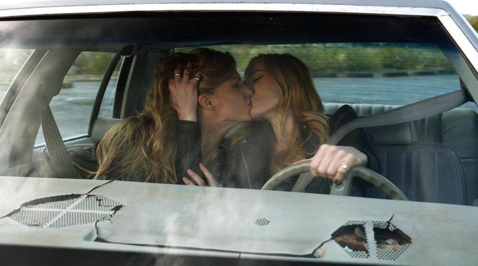 Ava and Sara passionately kiss while Sara drives them around.