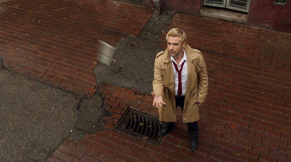 Constantine reaches out to catch the phone flying through the air.