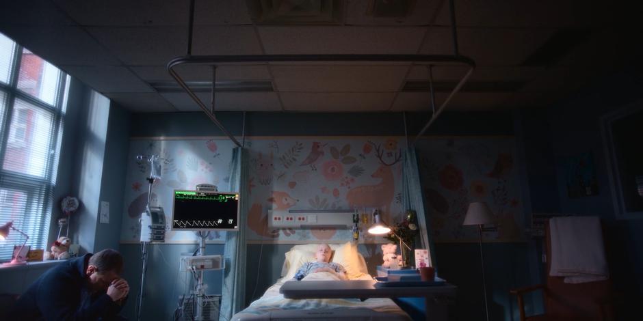 Director Stevenson sits praying beside his daughter's hospital bed.