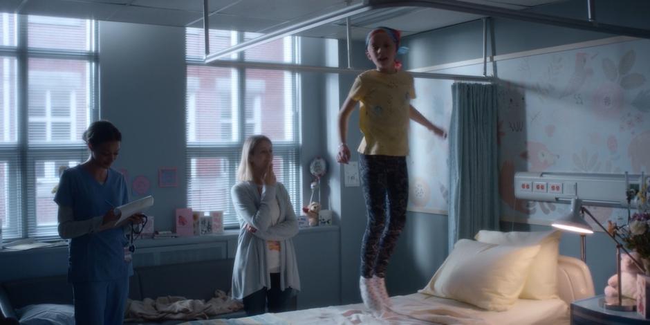 Director Stevenson's daughter jumps up and down on the bed while her mother watches in awe with the doctor.