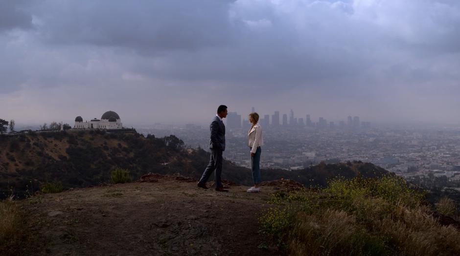 Jonah walks over towards Karolina with the Griffith Observatory and the downtown skyline in the background.