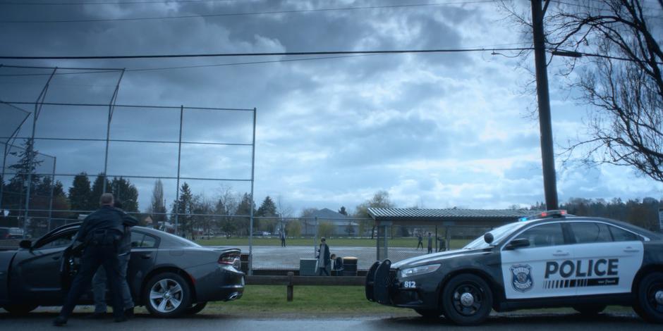 The officer cuffs Jeff against the side of his car.