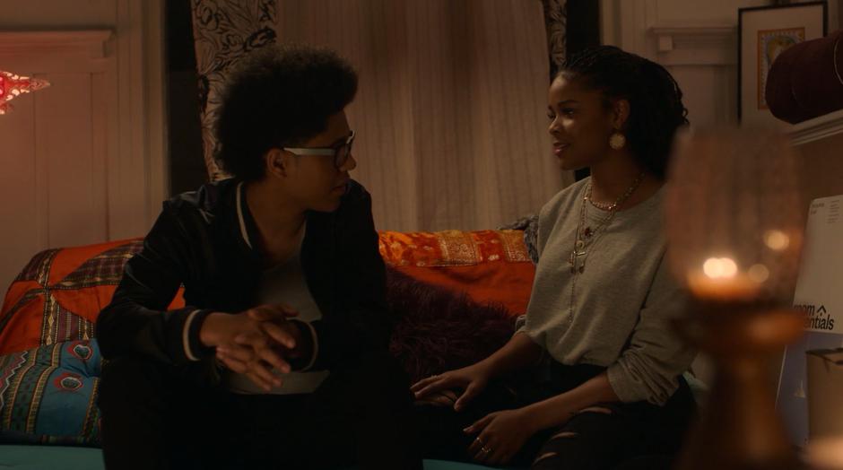 Alex and Livvie sit on her bed talking.